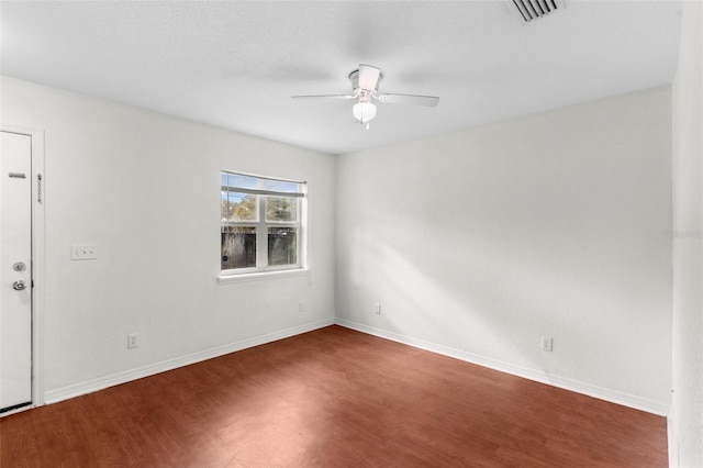 empty room with visible vents, ceiling fan, baseboards, and wood finished floors