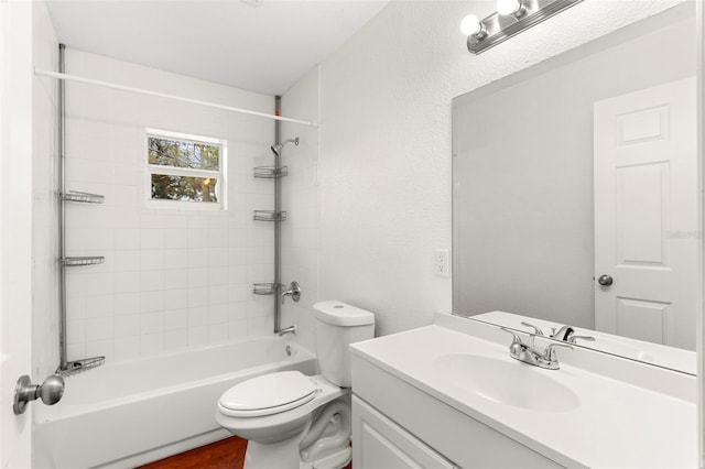 bathroom featuring a textured wall, shower / bathing tub combination, vanity, and toilet