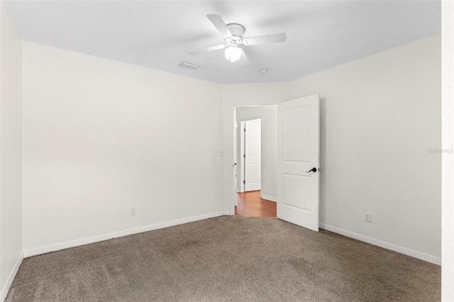 carpeted empty room with a ceiling fan, visible vents, and baseboards