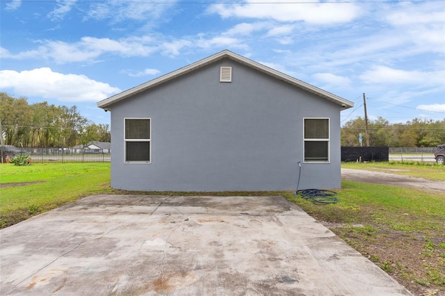 view of side of home featuring stucco siding, a yard, and fence