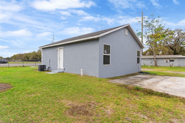 view of side of property with central AC unit, a lawn, a patio, fence, and stucco siding