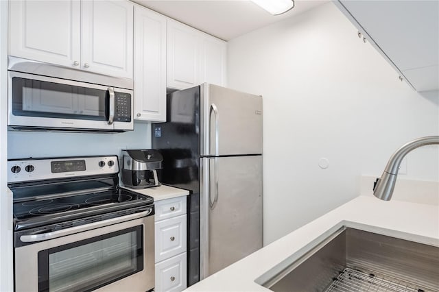 kitchen with white cabinets, a sink, stainless steel appliances, and light countertops