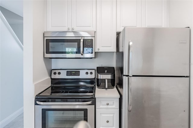 kitchen with stainless steel appliances, light countertops, white cabinetry, and baseboards