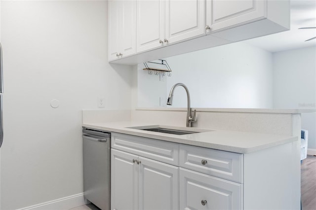 kitchen with baseboards, white cabinets, light countertops, stainless steel dishwasher, and a sink