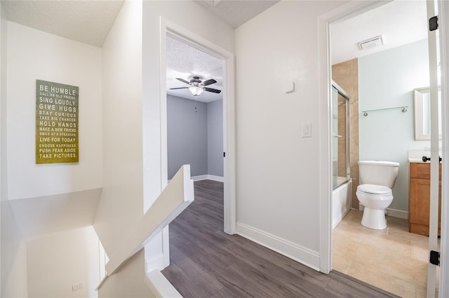 full bath with visible vents, toilet, combined bath / shower with glass door, vanity, and a textured ceiling