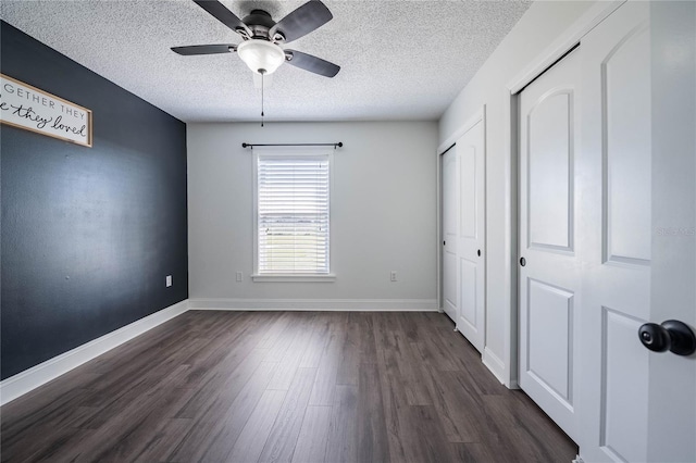 unfurnished bedroom with dark wood finished floors, a textured ceiling, baseboards, and ceiling fan