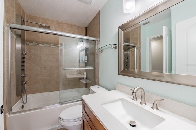 full bathroom featuring a textured ceiling, shower / bath combination with glass door, vanity, and toilet