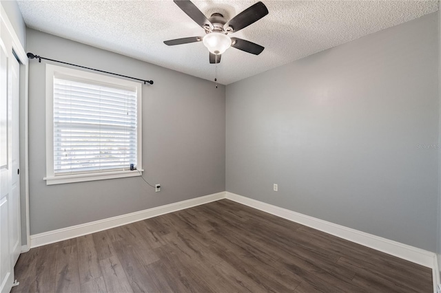 spare room featuring a textured ceiling, ceiling fan, dark wood-style flooring, and baseboards