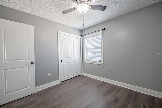 unfurnished bedroom with a textured ceiling, a closet, wood finished floors, and baseboards