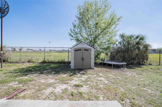 view of shed featuring a trampoline and fence