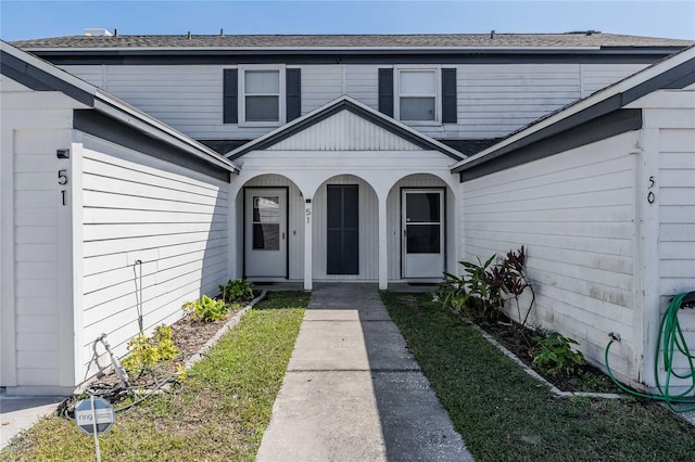 doorway to property featuring a shingled roof