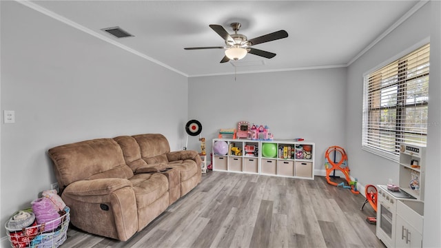 rec room featuring ceiling fan, light wood-style flooring, visible vents, baseboards, and crown molding