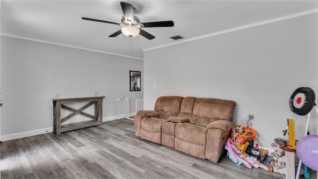 living room with crown molding, wood finished floors, visible vents, and baseboards