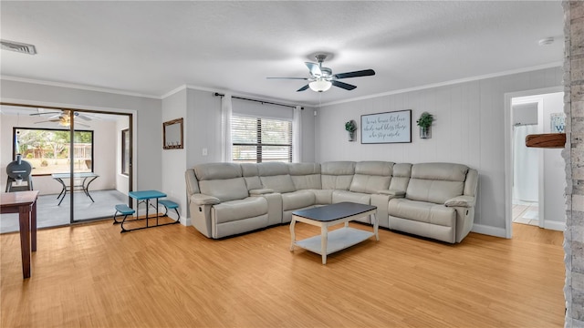 living room with light wood-type flooring, a wealth of natural light, visible vents, and crown molding