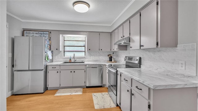 kitchen with under cabinet range hood, light wood-style floors, light countertops, appliances with stainless steel finishes, and crown molding