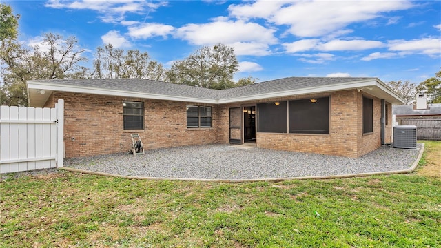 rear view of house featuring brick siding, central air condition unit, a lawn, a patio area, and fence