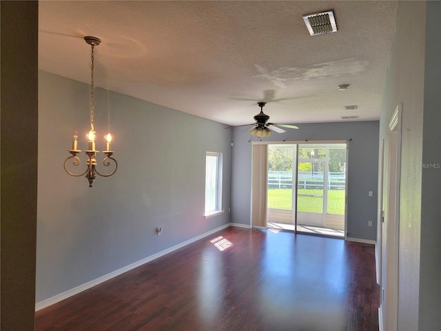 spare room featuring baseboards, visible vents, dark wood-style flooring, a textured ceiling, and ceiling fan with notable chandelier