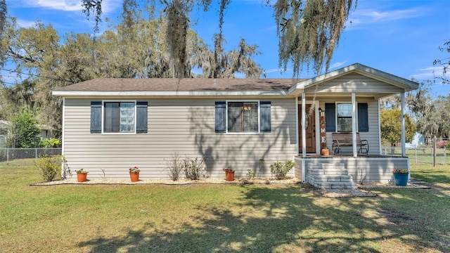 view of front facade with a front yard, covered porch, and fence