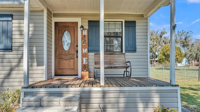 property entrance featuring covered porch and fence