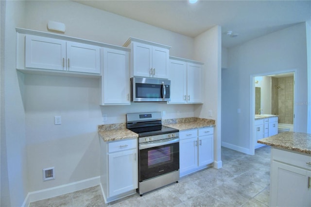 kitchen with stainless steel appliances, white cabinetry, light stone counters, and baseboards