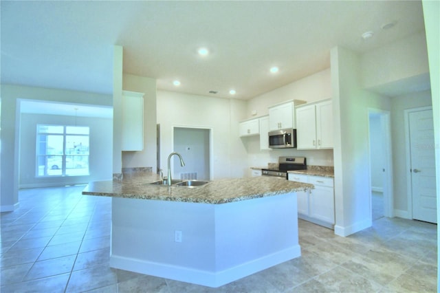 kitchen with light stone counters, a peninsula, a sink, white cabinets, and appliances with stainless steel finishes