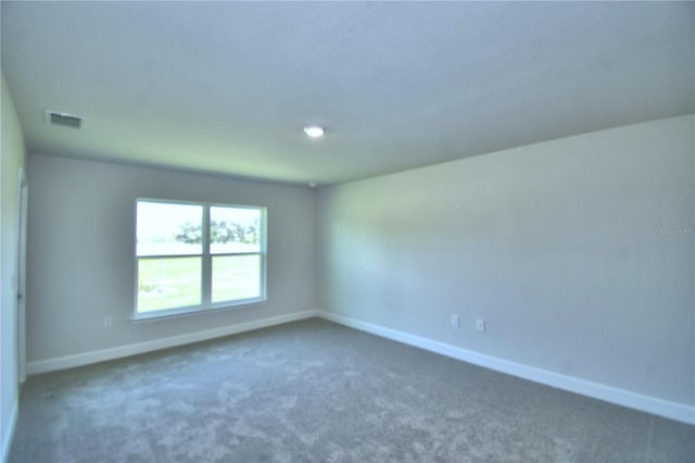 spare room featuring baseboards, visible vents, and dark colored carpet