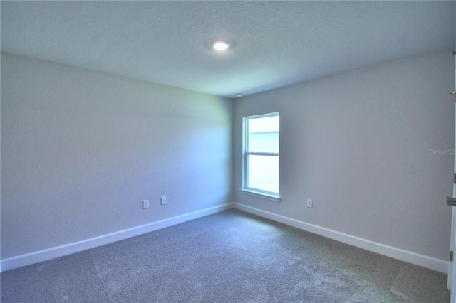 empty room with dark carpet and baseboards