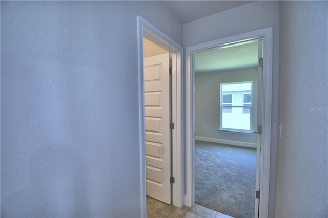 hall featuring light carpet and baseboards