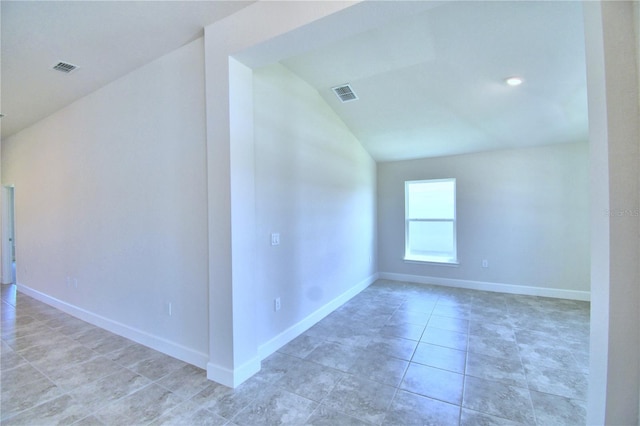 empty room featuring lofted ceiling, light tile patterned flooring, visible vents, and baseboards