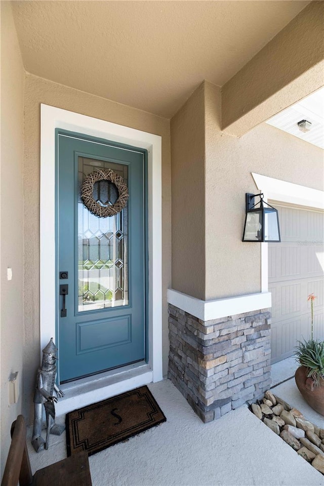 view of exterior entry with stone siding and stucco siding