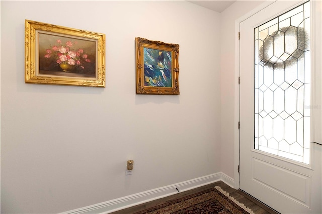 foyer entrance featuring dark wood-style flooring, plenty of natural light, and baseboards