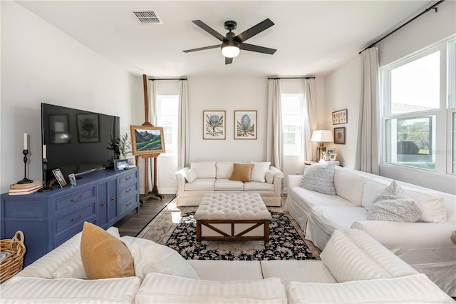 living room with a ceiling fan, visible vents, and wood finished floors