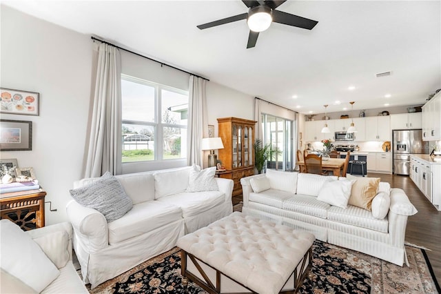 living area featuring dark wood-type flooring, a wealth of natural light, visible vents, and recessed lighting