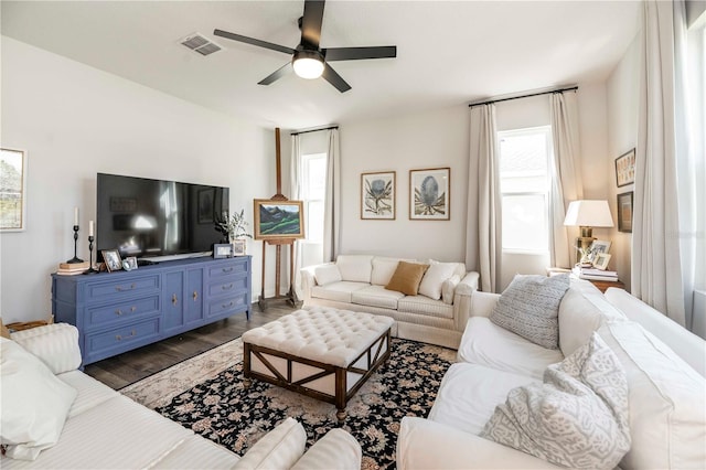 living room with visible vents, dark wood finished floors, and a ceiling fan