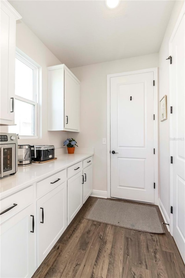 kitchen featuring light countertops, white cabinets, dark wood finished floors, and baseboards