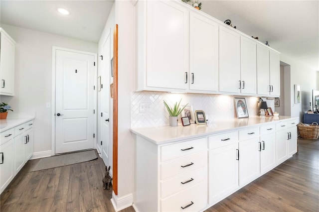 kitchen with dark wood finished floors, light countertops, decorative backsplash, white cabinetry, and baseboards