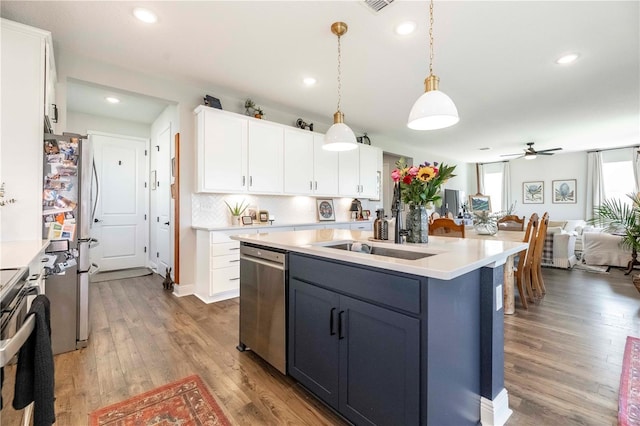 kitchen featuring stainless steel appliances, wood finished floors, white cabinets, open floor plan, and light countertops