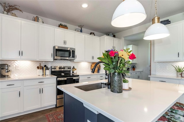 kitchen featuring a center island with sink, white cabinetry, and stainless steel appliances