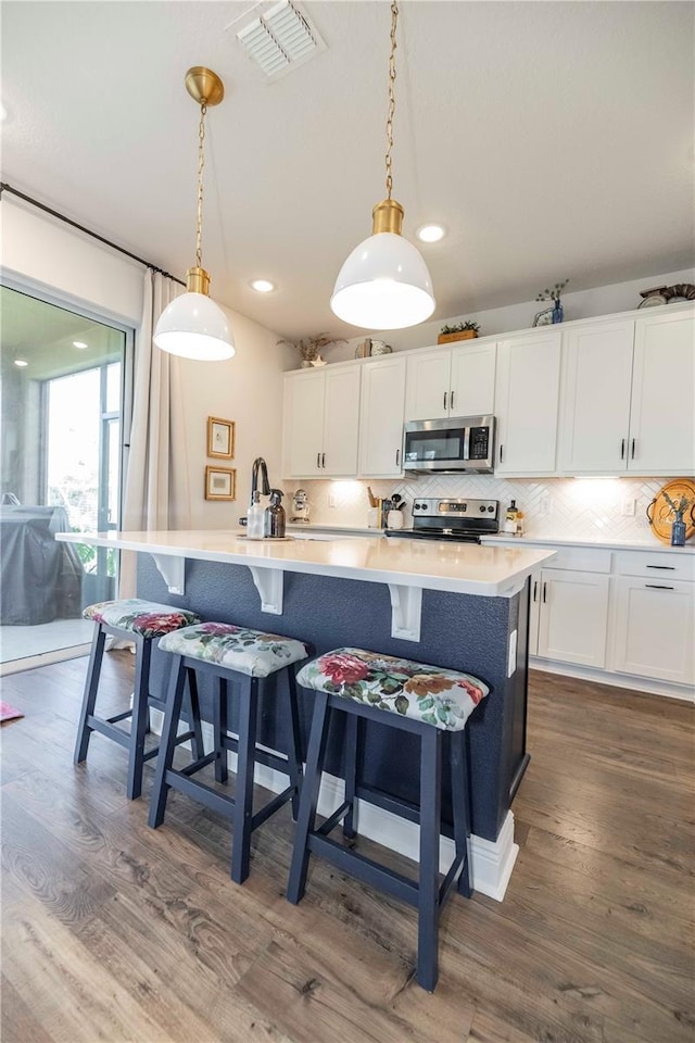 kitchen featuring stainless steel appliances, tasteful backsplash, dark wood-style flooring, and visible vents