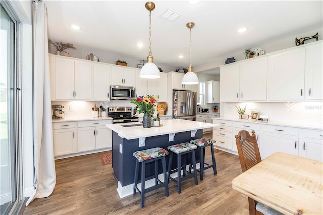 kitchen featuring wood finished floors, visible vents, white cabinetry, light countertops, and appliances with stainless steel finishes