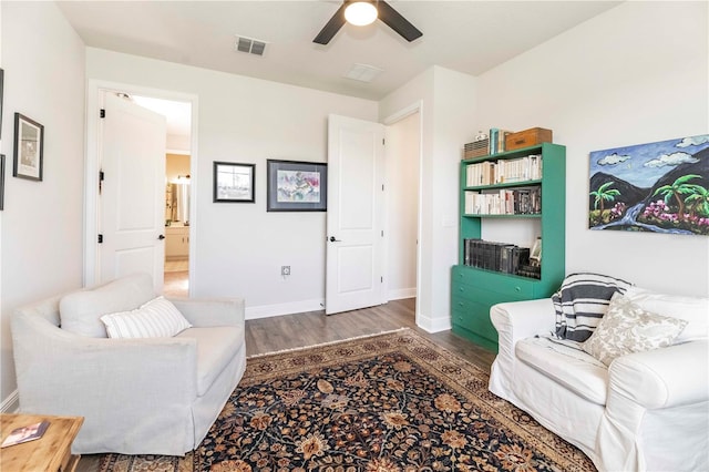 living area with visible vents, ceiling fan, baseboards, and wood finished floors