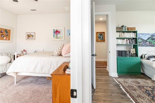 bedroom with visible vents, baseboards, and wood finished floors