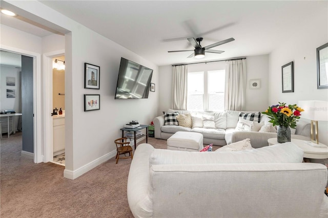 carpeted living area with a ceiling fan and baseboards