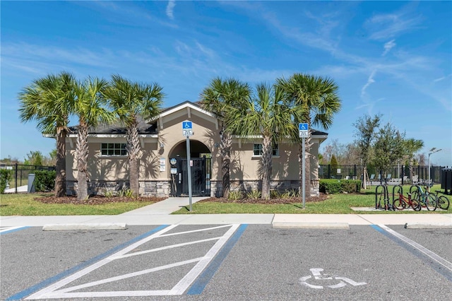 view of building exterior with uncovered parking and fence