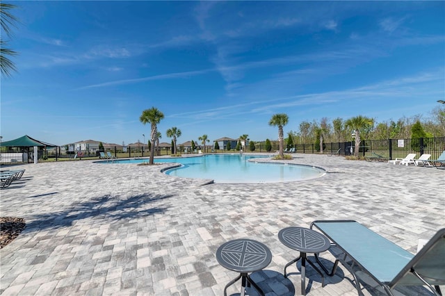 pool with a patio and fence