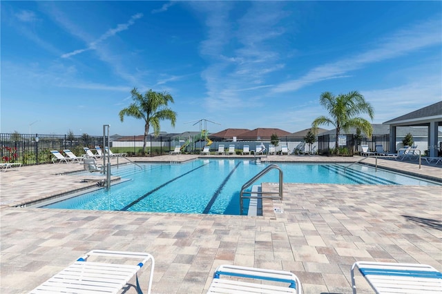 community pool with a patio area and fence