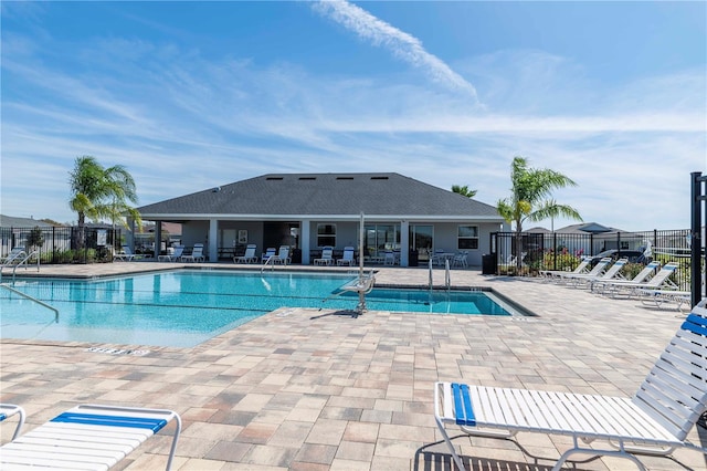 community pool with a patio area and fence