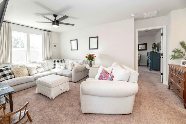 living area with ceiling fan, visible vents, and light colored carpet