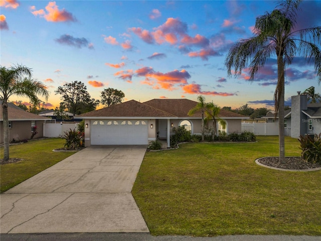 single story home with an attached garage, fence, concrete driveway, a lawn, and stucco siding