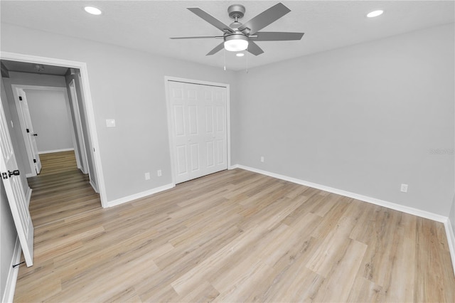 unfurnished bedroom featuring a textured ceiling, recessed lighting, baseboards, light wood-style floors, and a closet